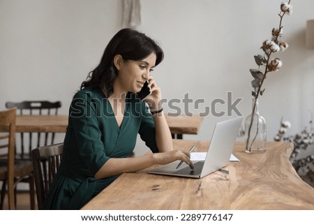 Businesswoman sits at desk, calling by business, provide consultation remotely, lead formal conversation to client, use laptop working in cozy office, make order engaged in workflow using modern tech