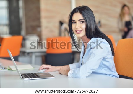 Businesswoman sits at a desk in front of a computer