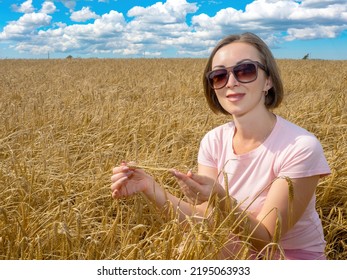 Businesswoman Sits In Wheat Field. Woman Holds Spikelets Wheat. Manager Of Agricultural Company. Agricultural Business Owner. Owner Grain Growing Company. Sky Over Wheat Field. Agricultural Industry