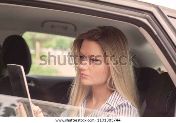 Businesswoman sitting in\
car holding\
tablet.