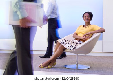 Businesswoman sitting in chair in busy office reception at camera - Powered by Shutterstock