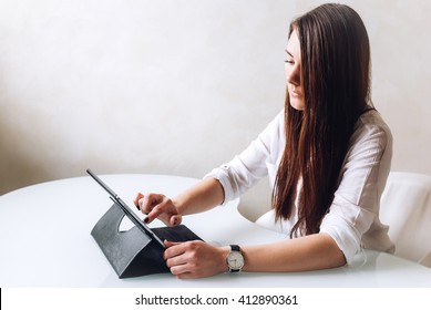 A businesswoman sitting in front of her table and working with a tablet  - Shutterstock ID 412890361