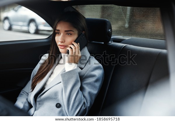 Businesswoman sitting in her car and talking on\
phone. Woman in businesswear making a phone call while sitting in\
her car.