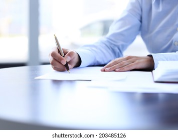 Businesswoman sitting at office desk signing a contract with shallow focus on signature - Powered by Shutterstock