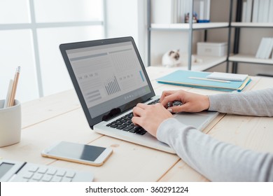 オフィスの机に座ってノートパソコンの手を接写したビジネスマン