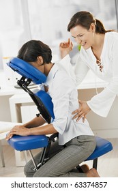 Businesswoman sitting on massage chair, enjoying back massage.?