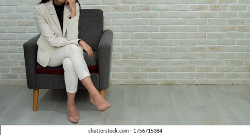 Businesswoman Sitting On Sofa With Crossed Legs.