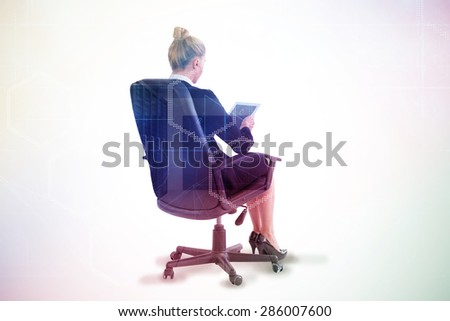 Businesswoman sitting on swivel chair with tablet against server room with towers