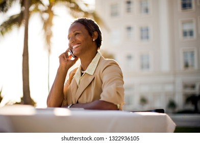 Businesswoman sitting at table outside, using cell phone. - Shutterstock ID 1322936105