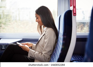 Businesswoman Sitting In Train Commuting To Work Checking Messages On Mobile Phone