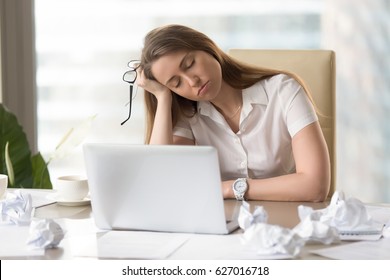 Businesswoman sleeping with head on hand at the desk. Sleepy girl dozing at workplace. Tired female office worker suffering from lack of sleep. Lazy girl bored routine. After-hours work in office 
