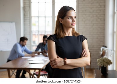 Businesswoman standing with arms crossed looks in window daydreaming about career growth, plan future deal feels confident. Promoted employee, head position independent woman, company owner concept