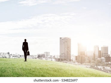 Businesswoman standing with back on top of hill and viewing modern city - Shutterstock ID 534822697