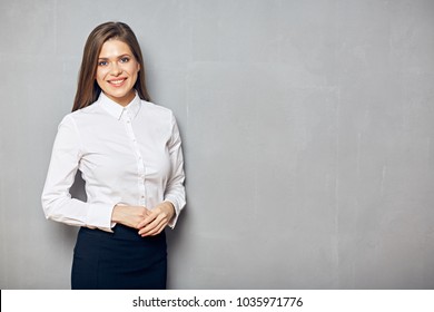 Businesswoman standing with folded hands. Smilng woman on gray wall background.