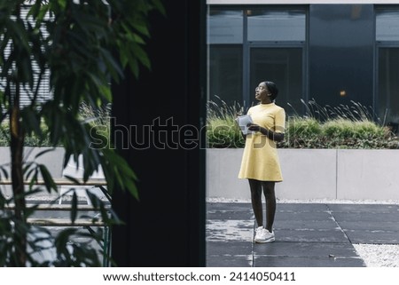 Businesswoman standing outside the office holding notebook