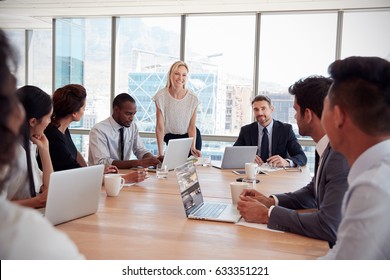 Businesswoman Stands To Address Meeting Around Board Table