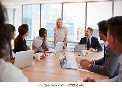 Businesswoman Stands To Address Meeting Around Board Table