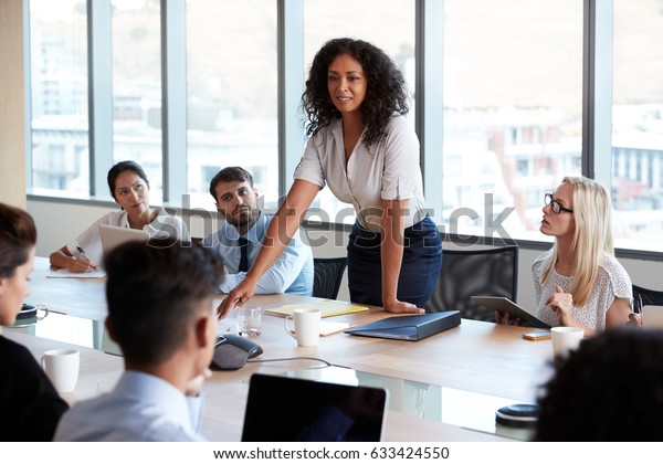 Businesswoman Stands To Address Meeting Around\
Board Table
