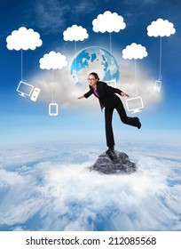 Businesswoman Stepping And Balancing Against Mountain Peak Through The Clouds