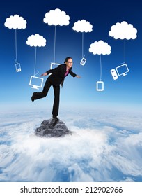 Businesswoman Stepping And Balancing Against Mountain Peak Through The Clouds