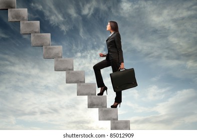 Businesswoman stepping up a stairway with sky in the background - Powered by Shutterstock