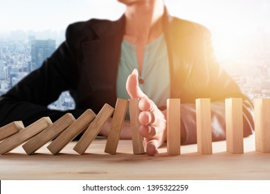 Businesswoman stops a chain fall like domino game. Concept of preventing crisis and failure in business. - Shutterstock ID 1395322259