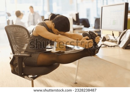 Businesswoman stretching legs with feet up on desk in office
