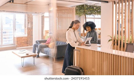 Businesswoman With Suitcase Checking In At Hotel Reception For Conference - Powered by Shutterstock