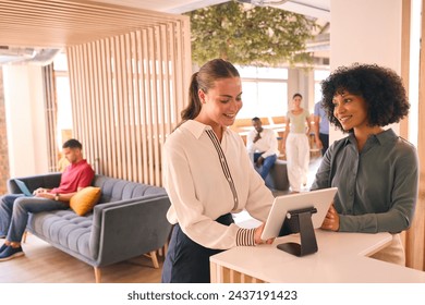 Businesswoman With Suitcase Checking In At Hotel Reception For Conference - Powered by Shutterstock