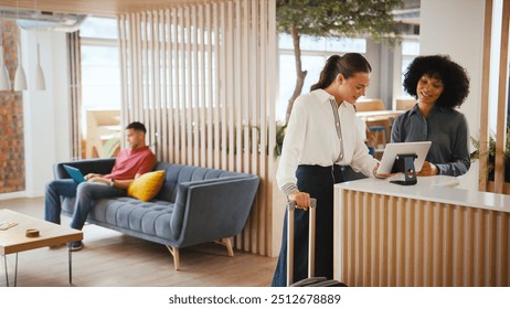 Businesswoman With Suitcase Checking In At Hotel Reception For Conference - Powered by Shutterstock