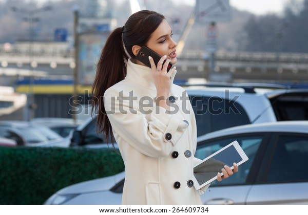 businesswoman with a tablet in his hand\
talking on the phone over city\
background