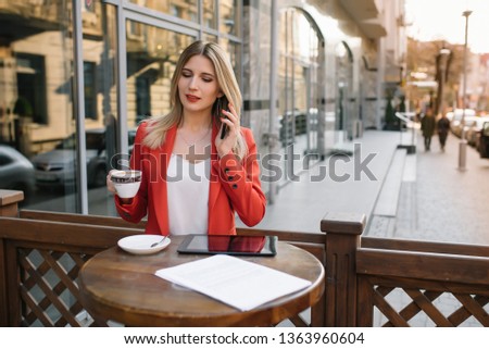 Businesswoman taking a coffee break and using smartphone.