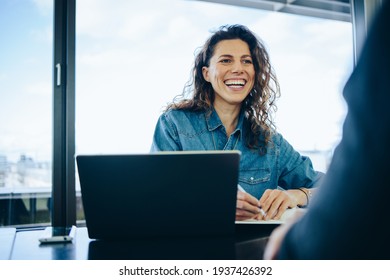 Businesswoman taking interview of a job applicant in office boardroom. Smiling recruiter asking questions to a male candidate during job interview.