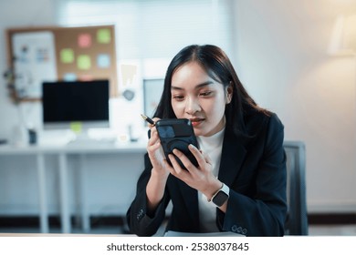 Businesswoman taking notes on her smartphone screen using a stylus pen, working on a new project in the office - Powered by Shutterstock