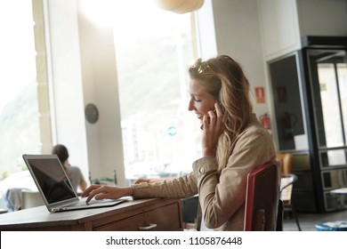Businesswoman Talking On Phone In Front Of Laptop, Sitting At Coffeeshop 