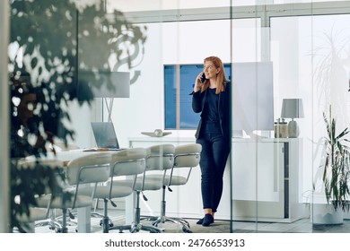 Businesswoman Talking on Smartphone in Modern Office Setting. - Powered by Shutterstock