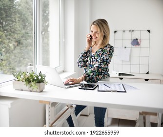 Businesswoman telephoning using cellphone while working at ergonomic standing desk.