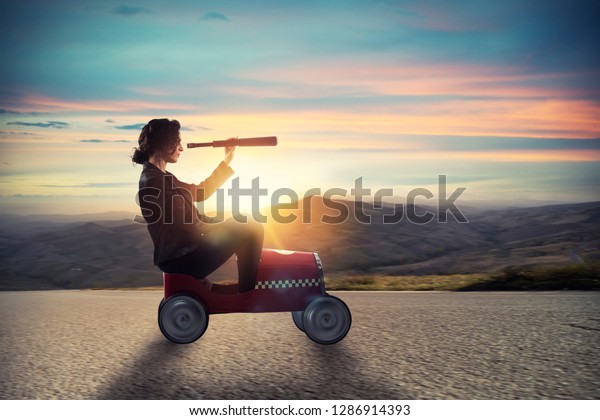 Businesswoman with telescope on a car looks\
for new business\
opportunity
