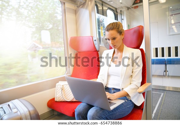Businesswoman in\
train connected on laptop\
computer