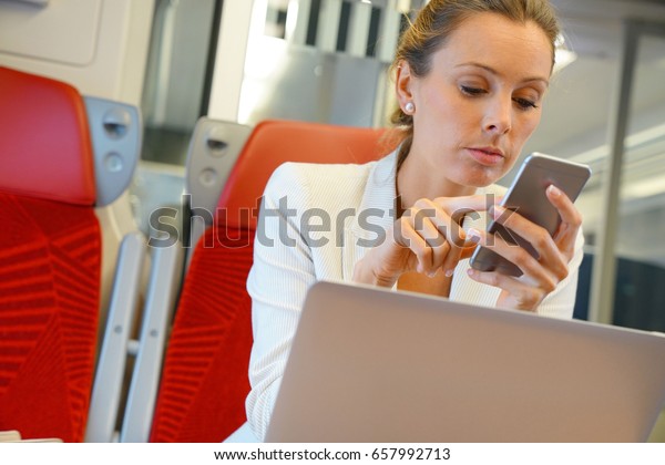 Businesswoman in train working on laptop and
talking on phone