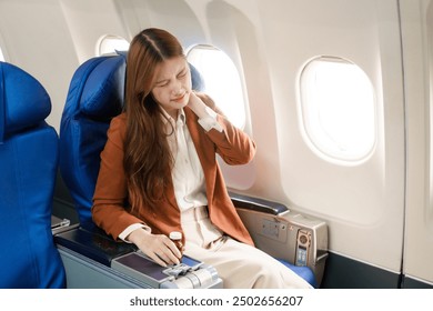 A businesswoman travels abroad on a plane, using her computer during the flight. She experiences jet lag, suffering from headaches, neck pain, and stomach ache due to the long journey. - Powered by Shutterstock