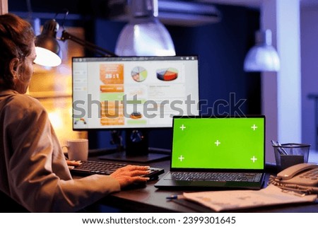 Businesswoman typing marketing strategy while analyzing with green screen chroma key mock up laptop computer with isolated display. Executive manager working overtime at investment plan