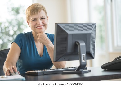 Businesswoman Using Computer At Desk In Office