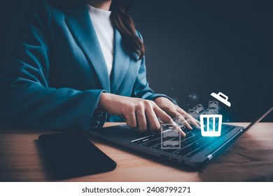 Businesswoman using computer laptop or smartphone delete files  from a computer or from the Internet. Concept of deleting files, contacts, putting in order, cleaning service, trash can and files. - Powered by Shutterstock