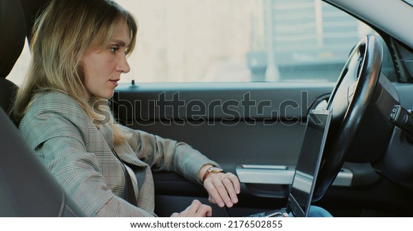Businesswoman using\
laptop computer in the car, using modern technology. Using\
technologies in the car\
concept.