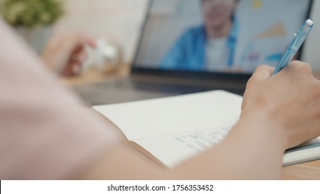 Businesswoman using laptop making video call conference with colleagues and talking, discussing business project online while she taking note on paper, write a report working from home and Remote work - Powered by Shutterstock