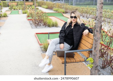 A businesswoman using a laptop on a golf course - Powered by Shutterstock