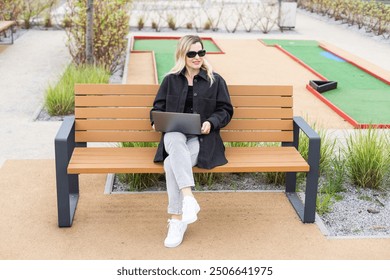 A businesswoman using a laptop on a golf course - Powered by Shutterstock