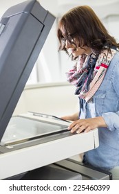 Businesswoman Using Photocopier In Creative Office