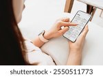 Businesswoman using smartphone with monthly calendar to plan 2025 activities. Scheduling and organizing plans. Technology and business concept.